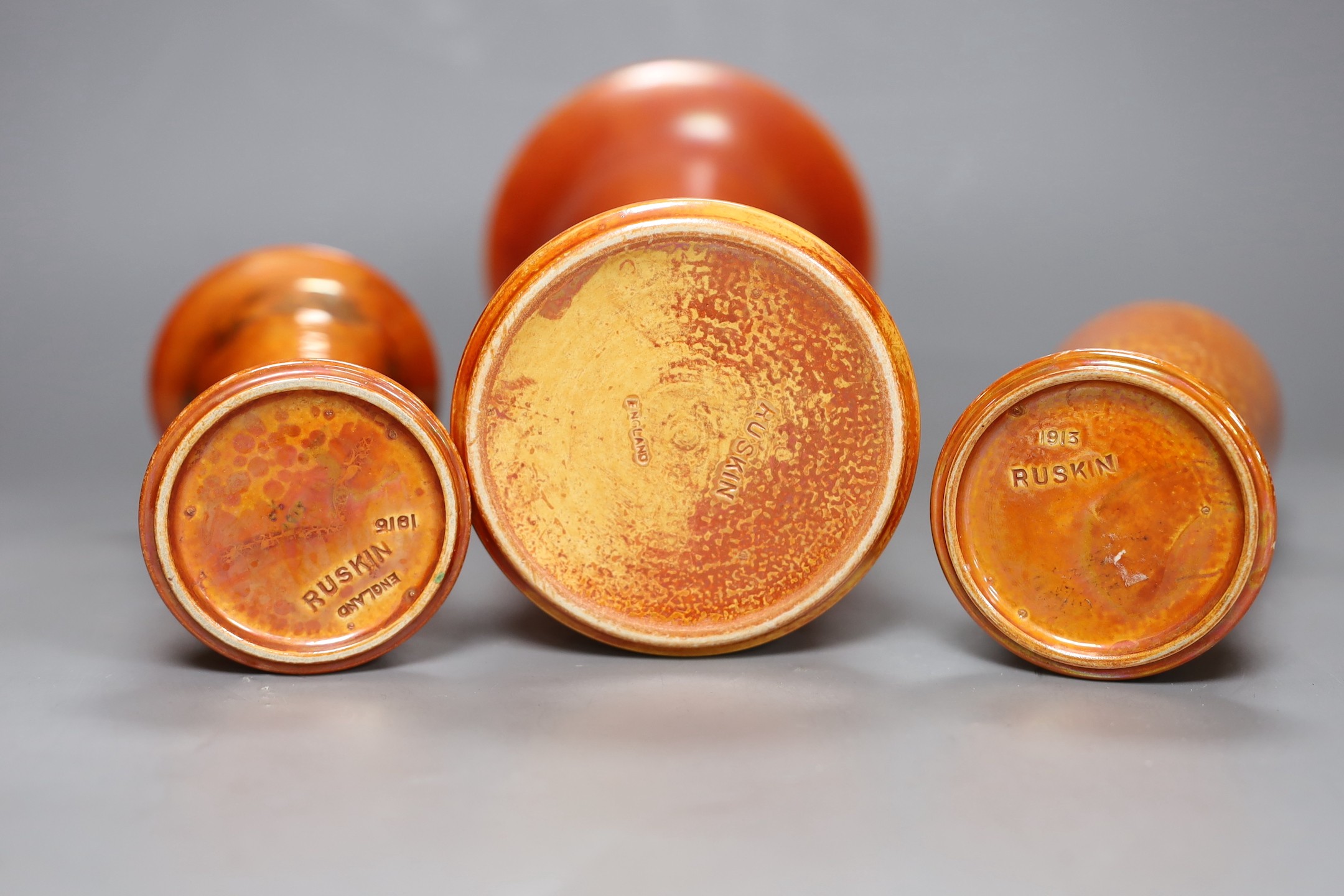 A group of three Ruskin orange lustre vases, largest 25cm